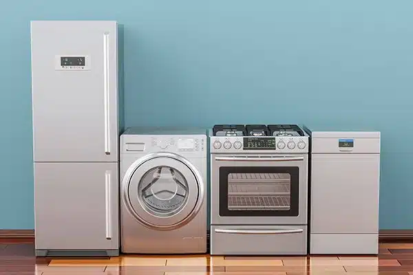 a fridge, washer, stove, and mini fridge appliances lined up in front of a blue wall