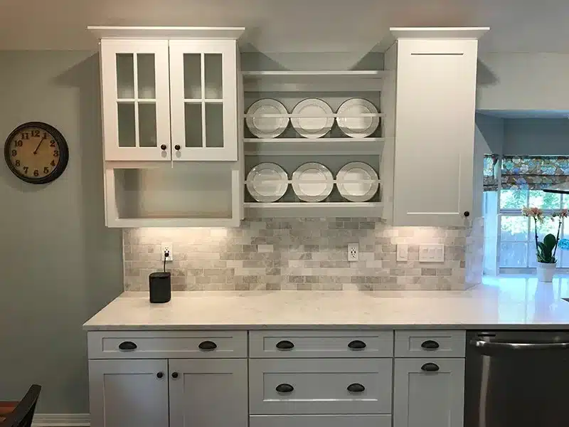 Built-in hutch with glass-front cabinet doors, an open plate rack, a gray stone tile backsplash, and under-cabinet lighting