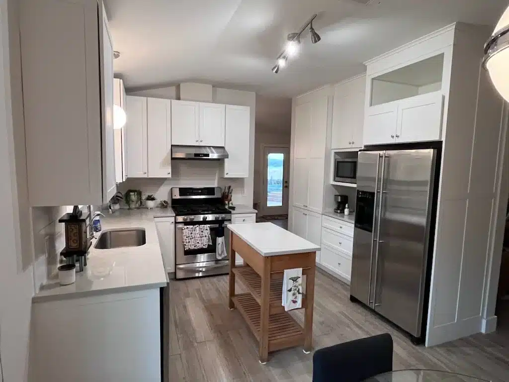White Shaker cabinets with tall pantry cabinets framing a stainless refrigerator, a built-in microwave shelf, and a gas range
